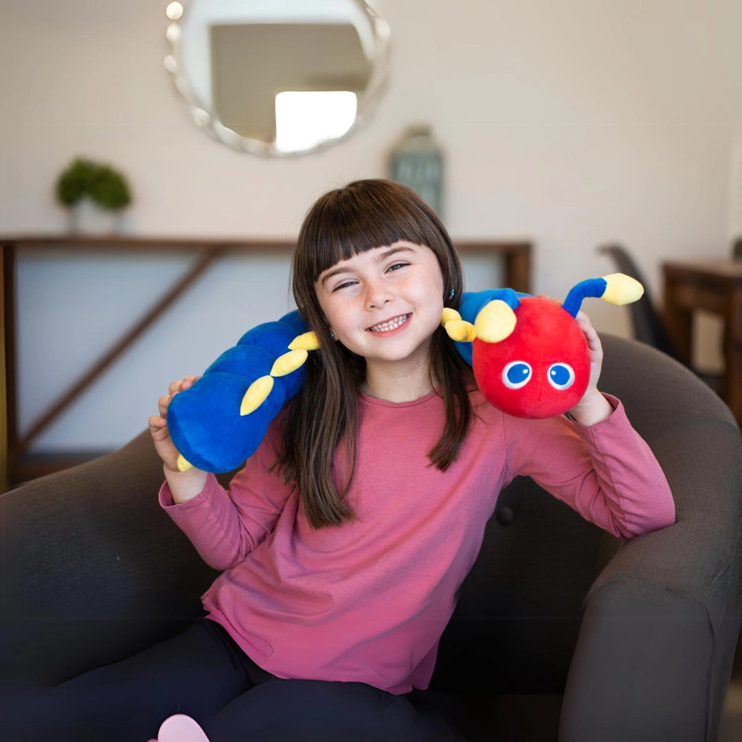 Young girl smiling while holding a colorful calming caterpillar weighted plush, sensory toy for kids.