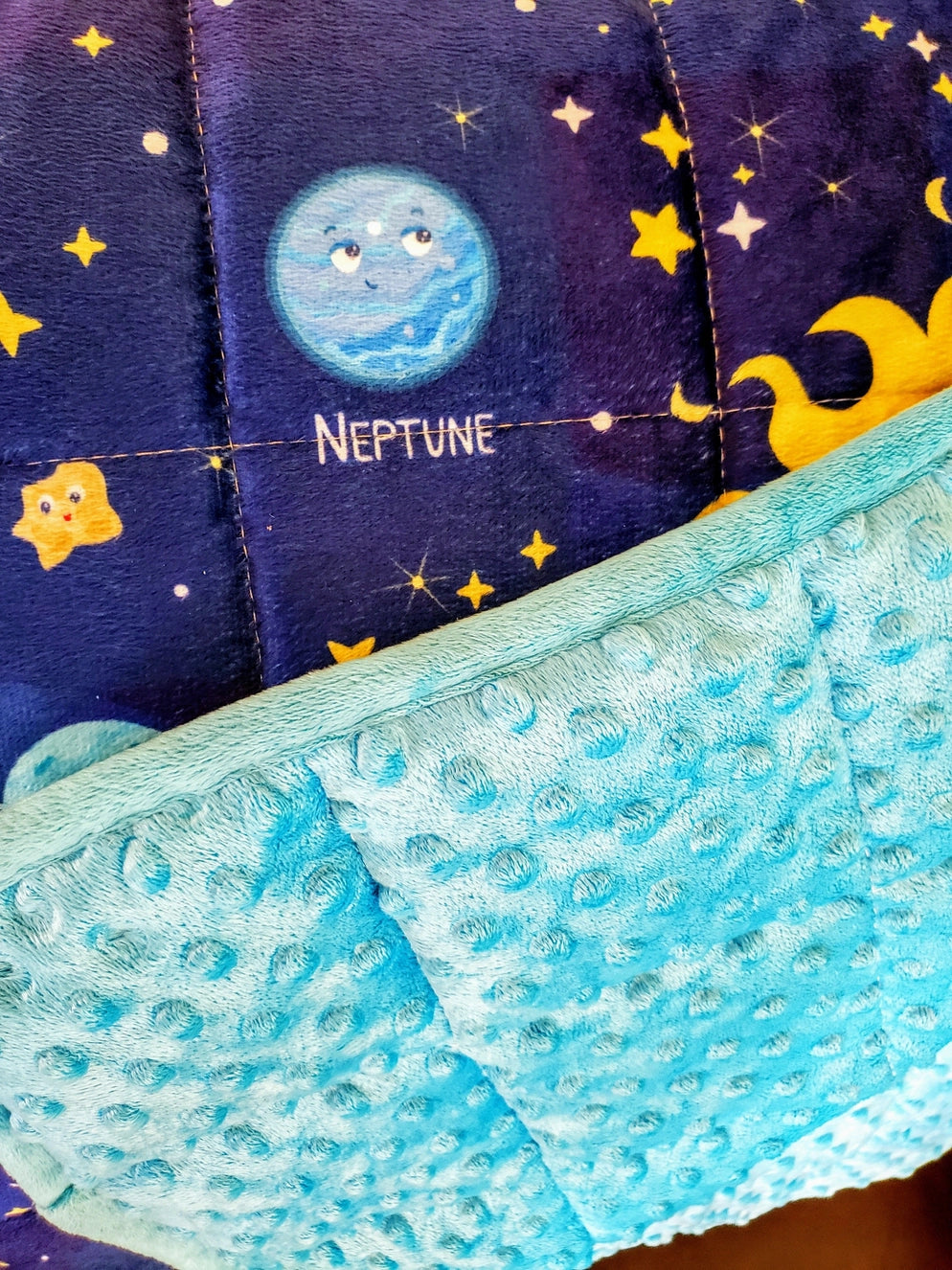 Close-up view of the Solar System weighted blanket featuring Neptune embroidery and soft blue minky texture. This 5 lb sensory calming blanket helps kids relax, focus, and sleep better — part of Zula Autism Mart’s sensory comfort collection.