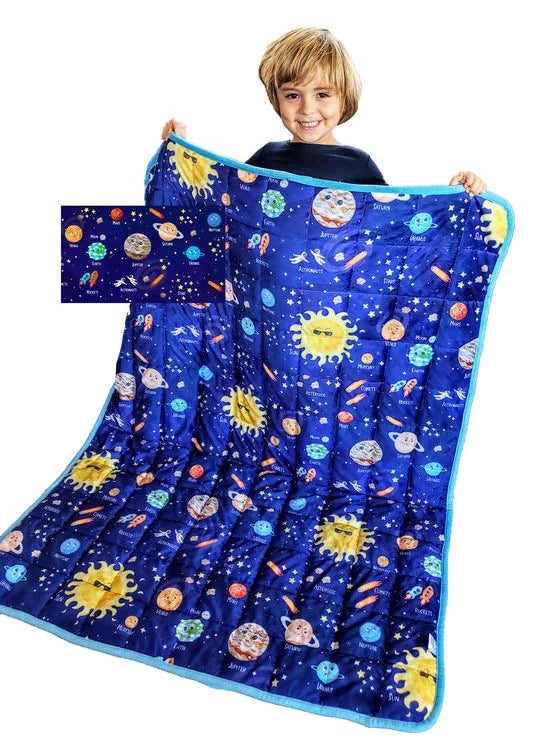 Child smiling while holding a Solar System weighted blanket for kids — sensory-friendly, 5 lb calming comfort blanket designed to promote relaxation, focus, and better sleep. Perfect for children dealing with autism or anxiety.