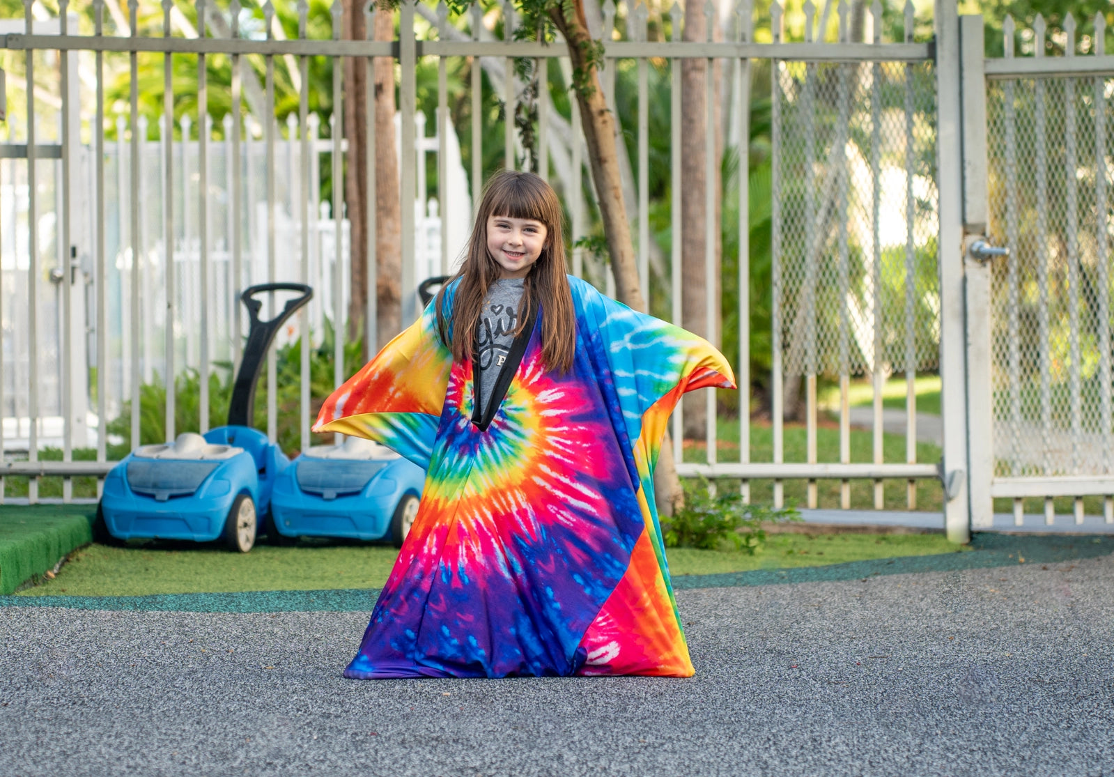 Child wearing a colorful tie-dye sensory compression blanket outdoors, designed for calm and fun movement.
