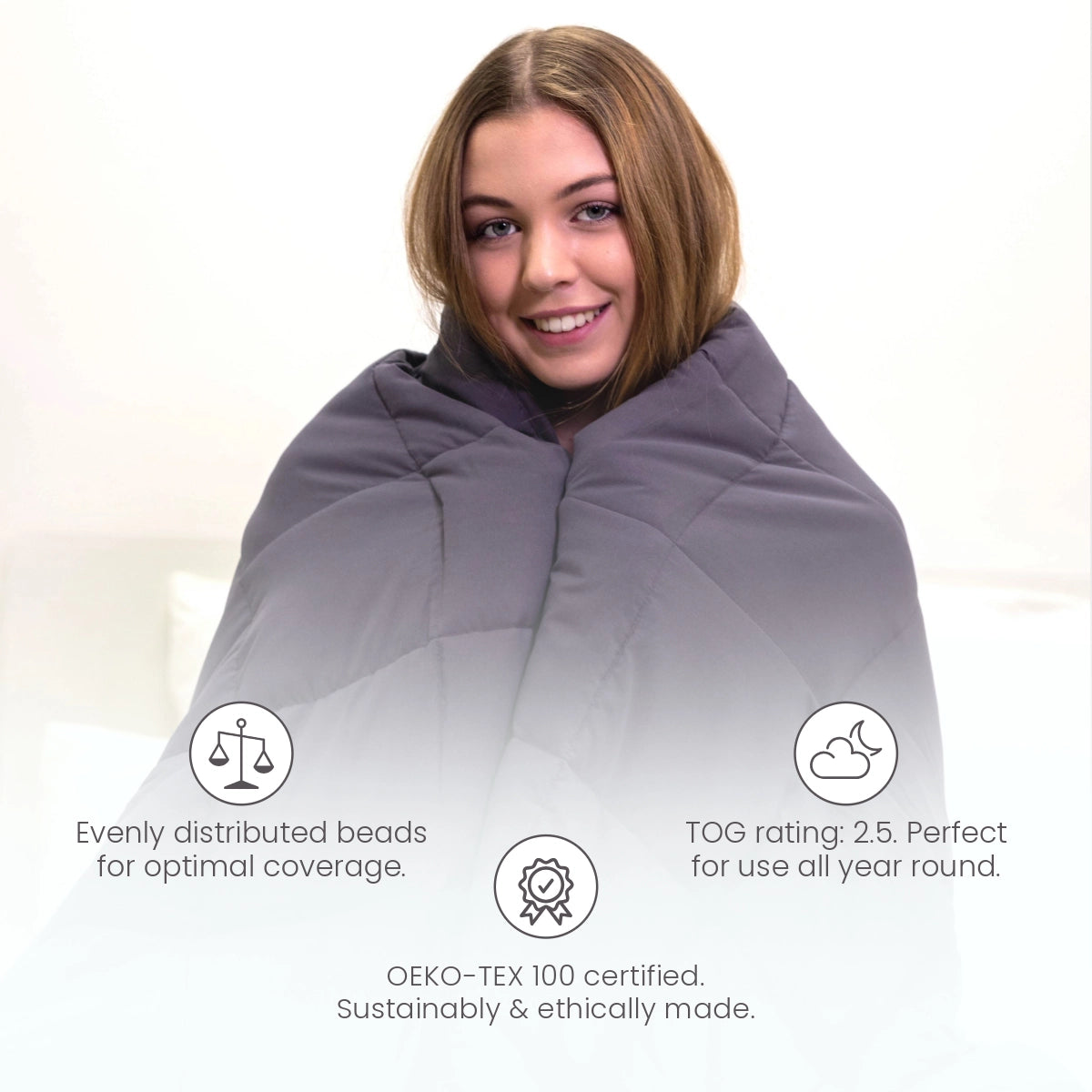 Woman wrapped in charcoal gray weighted blanket — evenly distributed glass beads, year-round comfort, OEKO-TEX certified, anxiety and stress relief.
